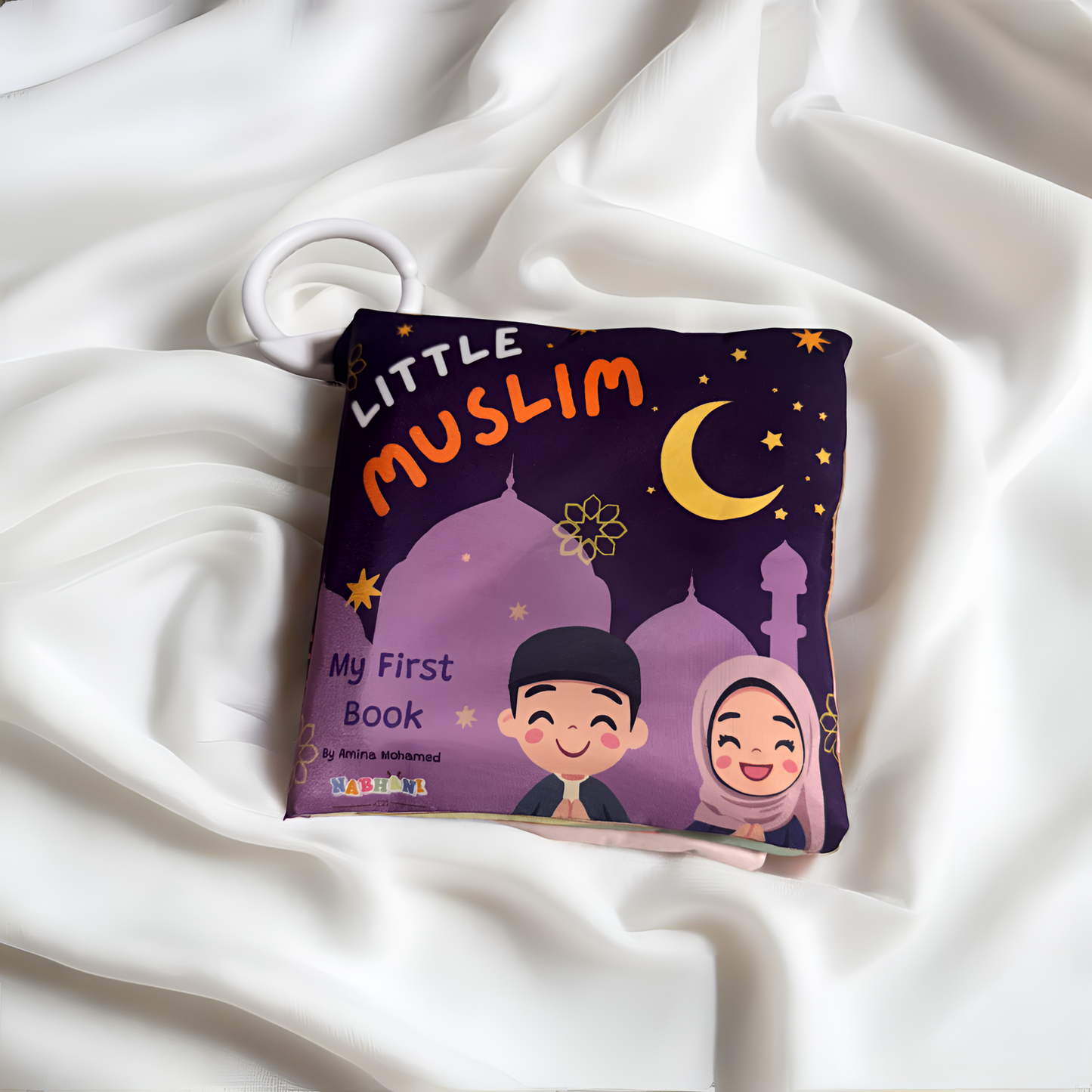 Children's book titled 'Little Muslim: My First Book' on a white fabric background